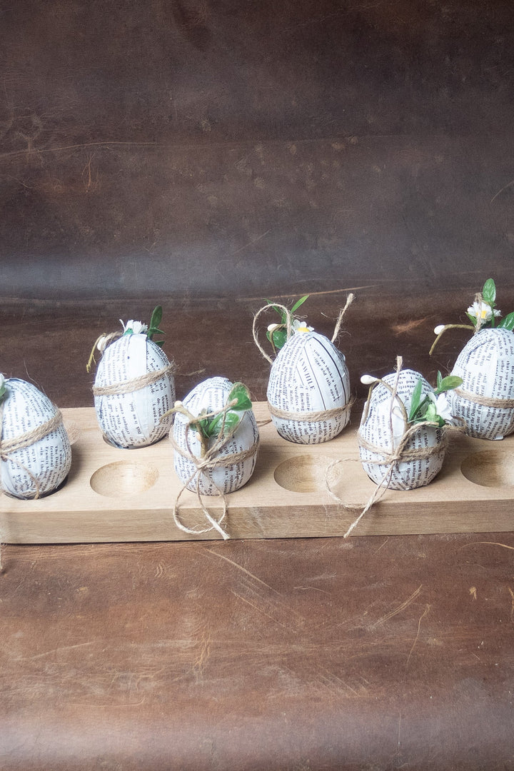Wooden egg holding tray with round wells, holding decorated eggs