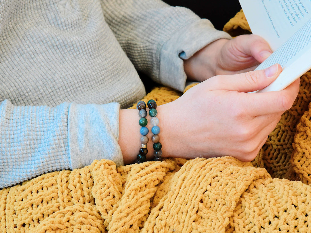 Beaded bracelet on wrist with blue, green, brown, and white round stone beads