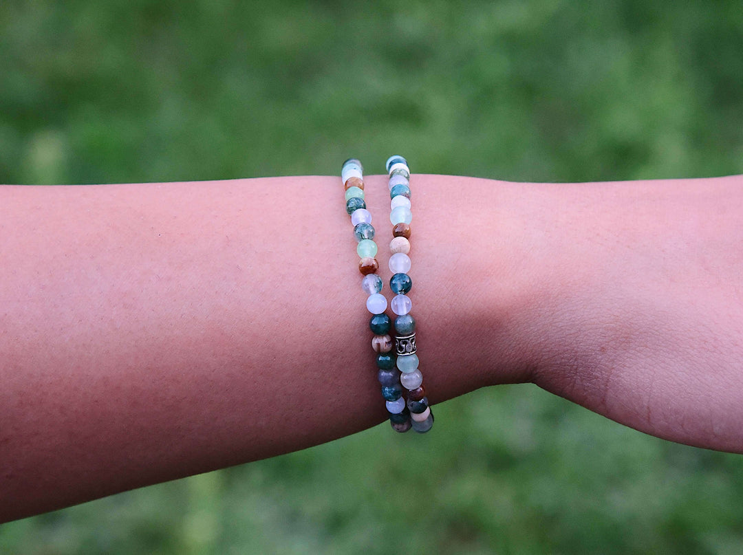 Mini beaded bracelet on wrist with multicolor round beads and a dark center detail.
