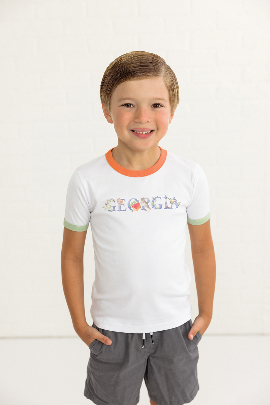 Kids white organic cotton tee with orange neck trim, green sleeve cuffs, Georgia logo