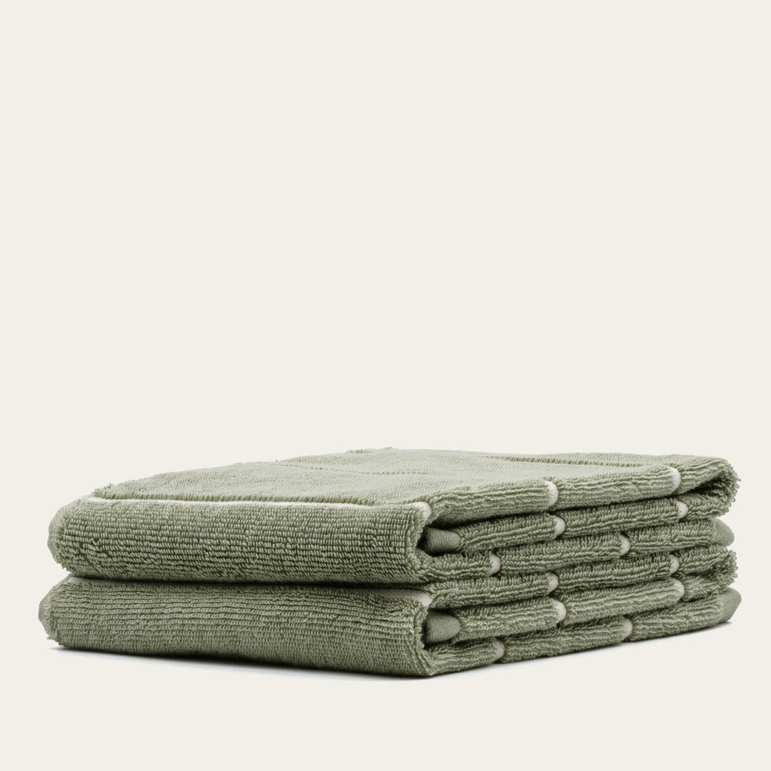 Sage green cotton towel set, stacked bundle of six folded terry towels.