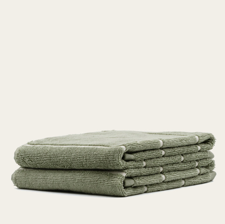 Sage green cotton towel set, stacked bundle of six folded terry towels.