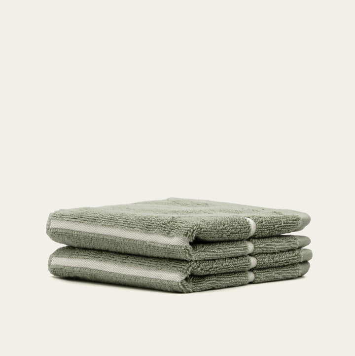 Sage green cotton bath towels, stack of three folded terry towels.