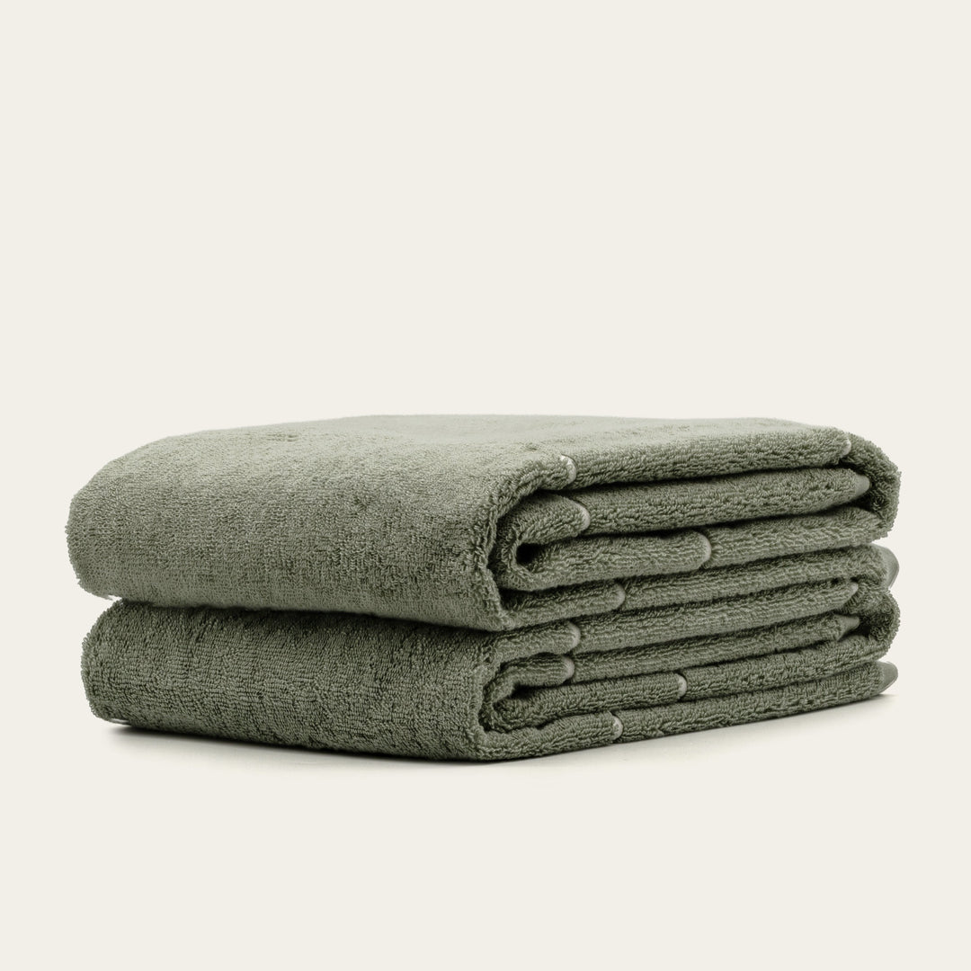 Folded sage green cotton towels, neatly stacked