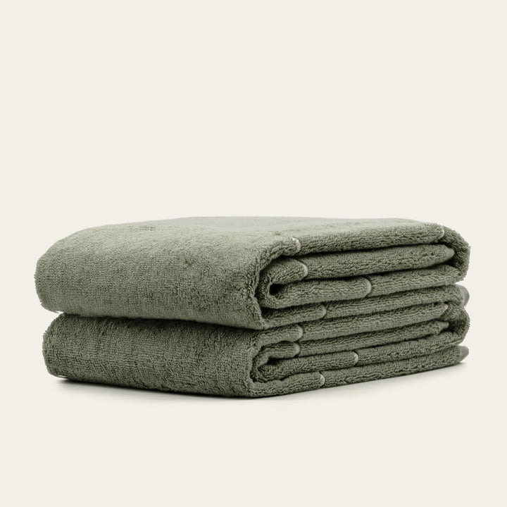 Folded sage green cotton towels, neatly stacked