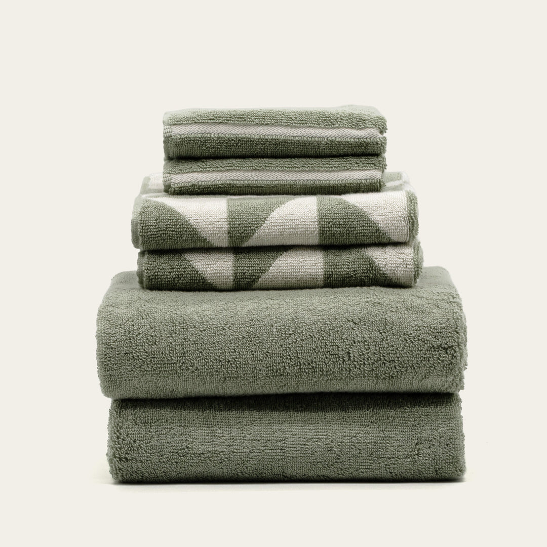 Sage green cotton bath towels, folded stack of four with textured terry loops.