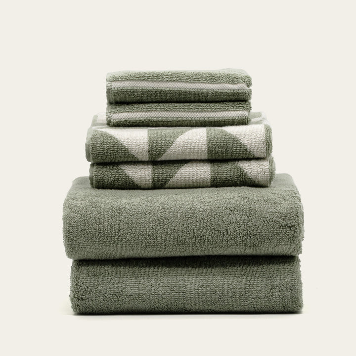 Sage green cotton bath towels, folded stack of four with textured terry loops.