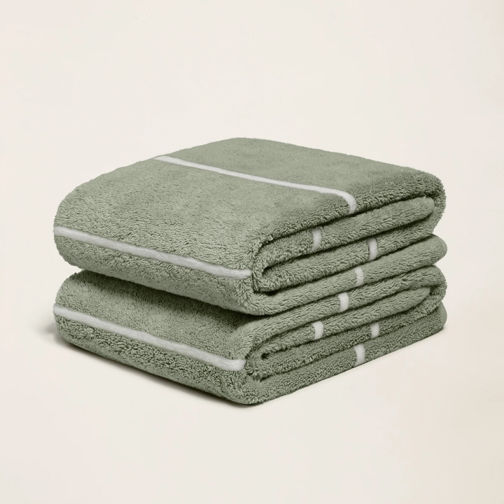 Sage green cotton towel with ecru striped band, folded in a stack