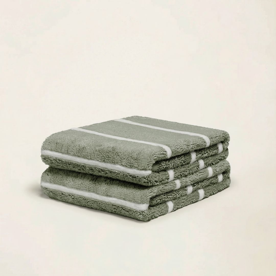Sage-green cotton towels stacked with white stripe bands along the edges