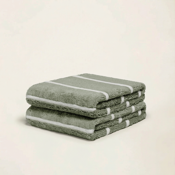 Sage-green cotton towels stacked with white stripe bands along the edges