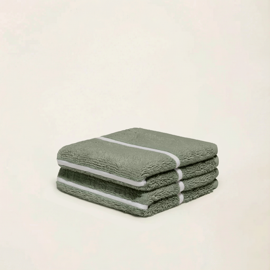 Stacked sage green cotton towels with ecru stripe detail