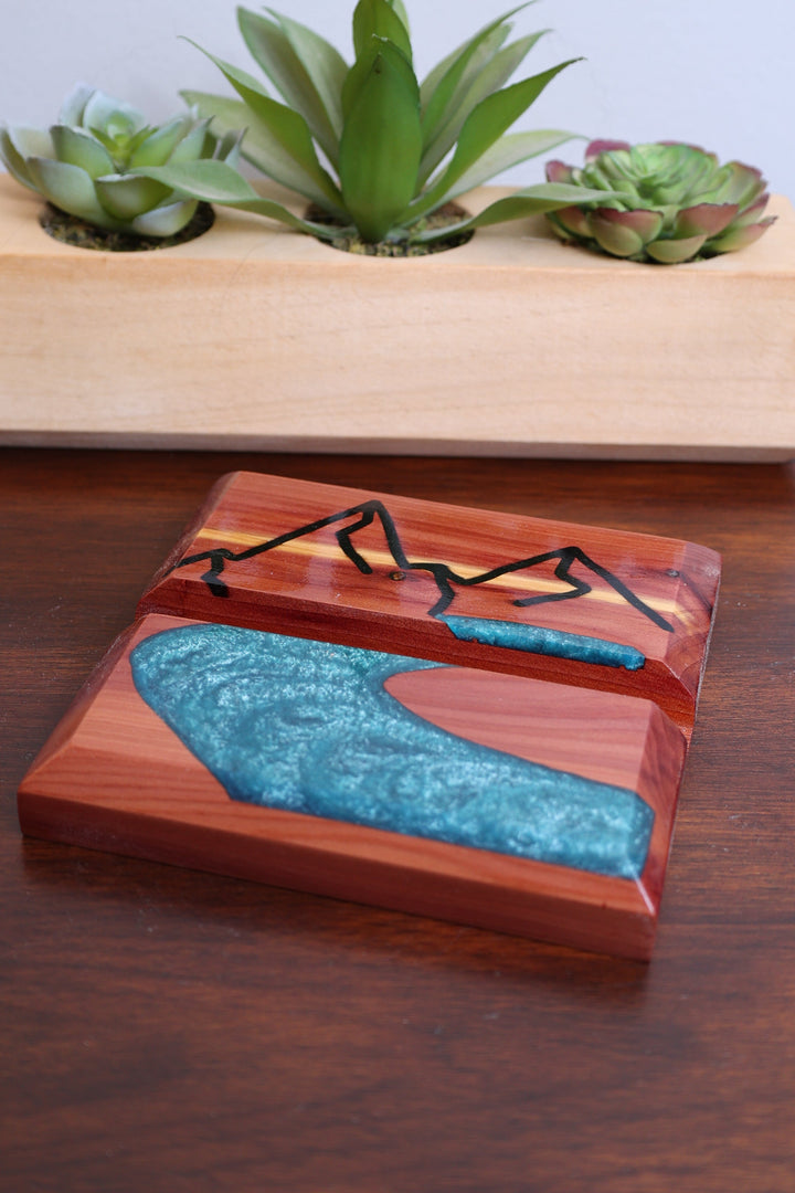 Wood and resin phone holder with blue river inlay, angled view, carved groove