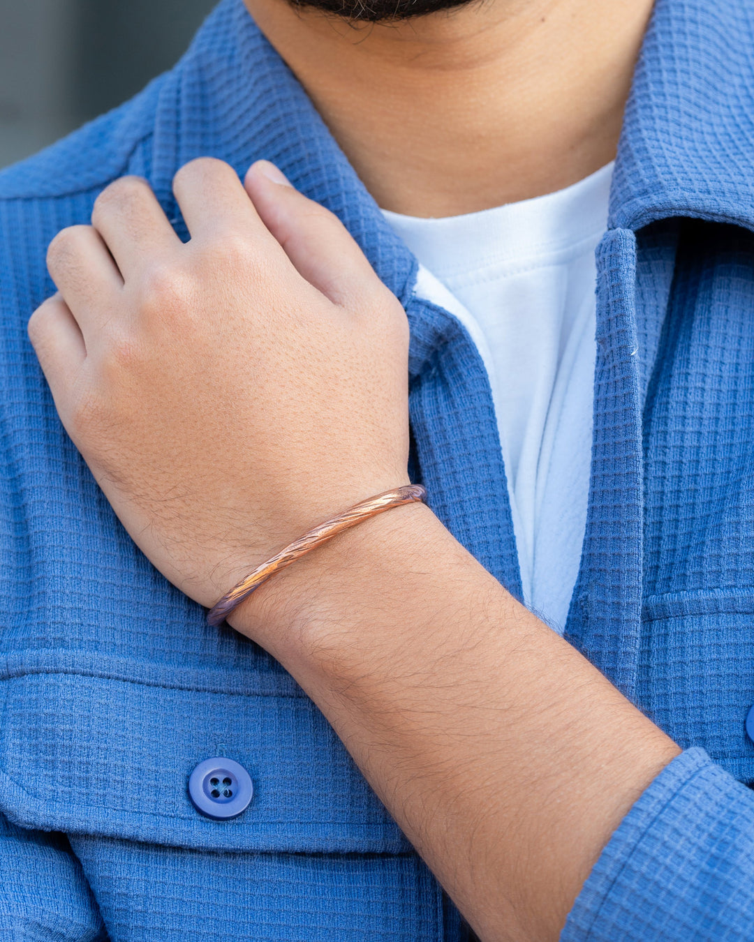 Solid copper cuff bracelet on wrist with braided distressed finish, close-up