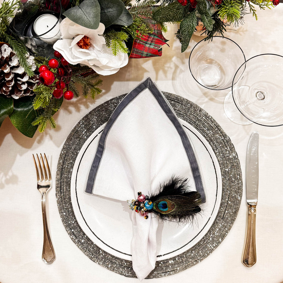 Linen napkins with dark velvet trim, folded and ring-secured on a place setting