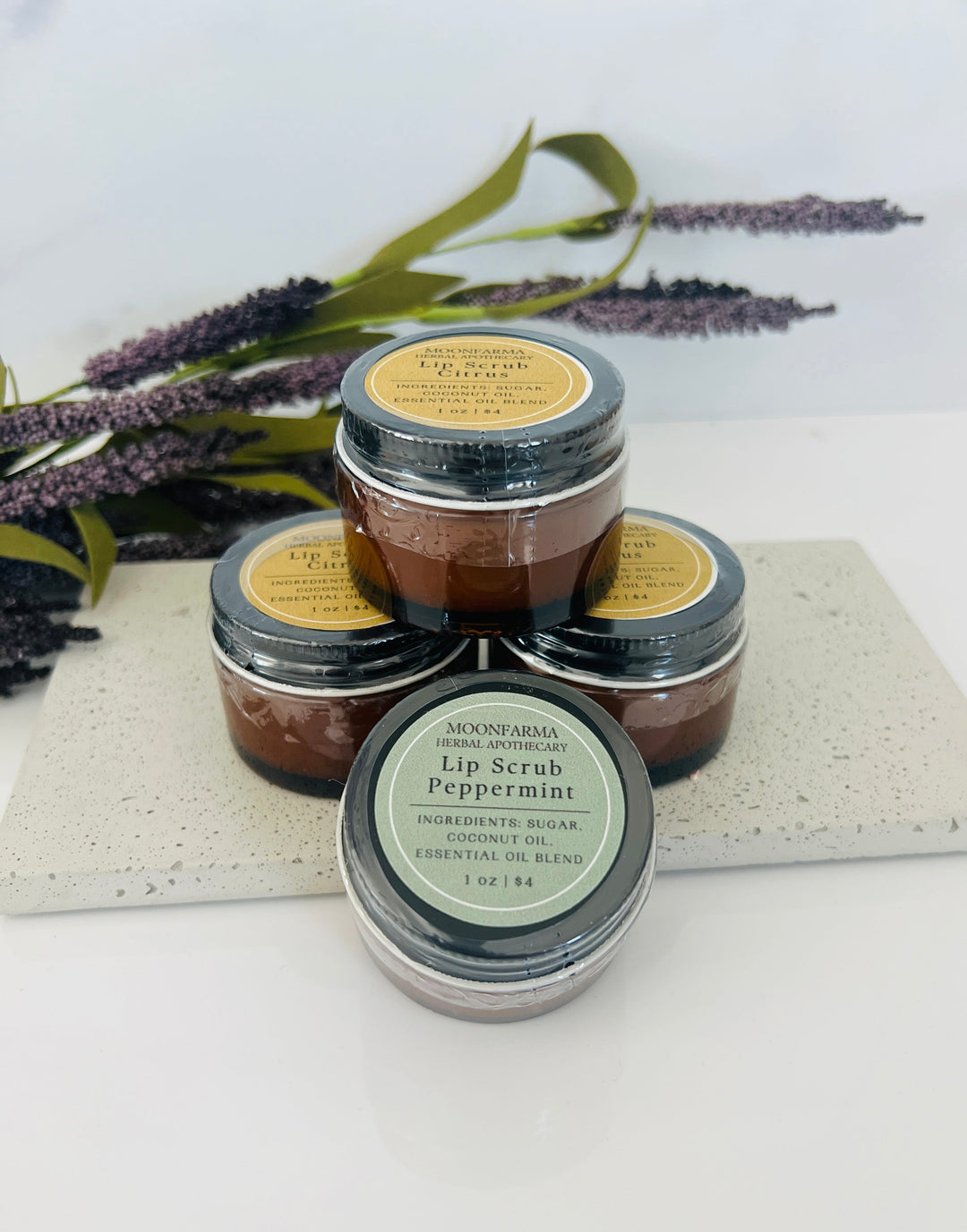 Three lip scrub jars: Peppermint and Citrus, dark brown scrub in round containers