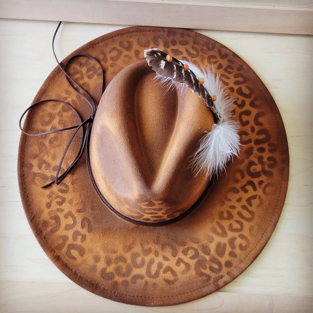Leopard-print tan cowgirl hat with feathered front detail and dark rope band