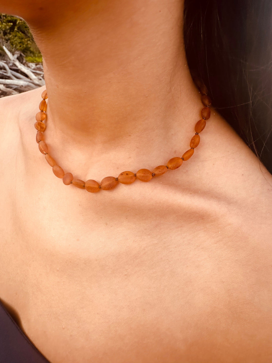Cognac amber bead necklace worn on neck, close-up of faceted oval beads