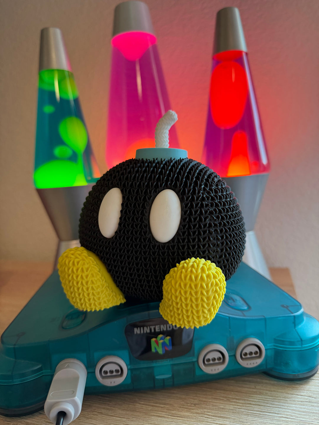 Black knitted bob-omb plush with cream eyes and yellow knitted side arms
