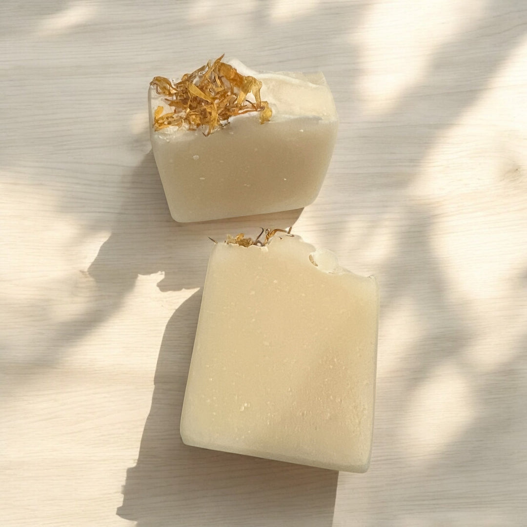 Cream soap bar topped with gold flake accents; two bar views shown