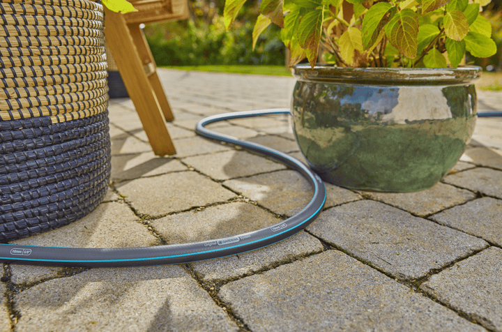 Garden hose line on pavement with blue-striped hose and connected nozzle