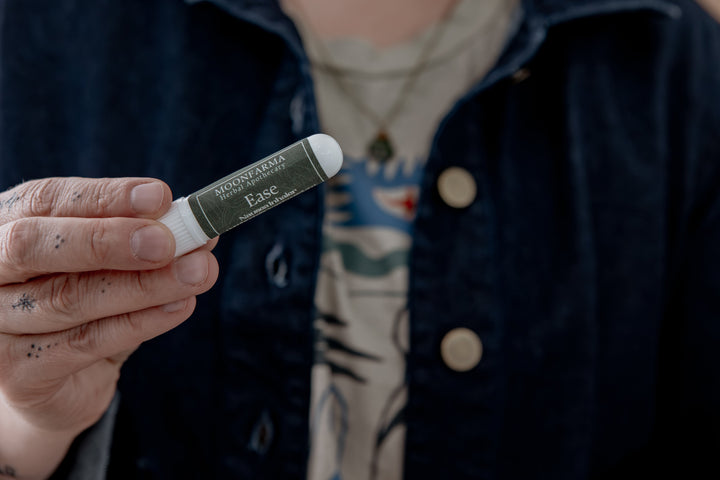 Dark green aromatherapy inhaler tube with Ease label, held in hand.
