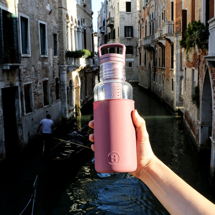 Wine-red 20 oz water bottle with flip-top lid held in one hand