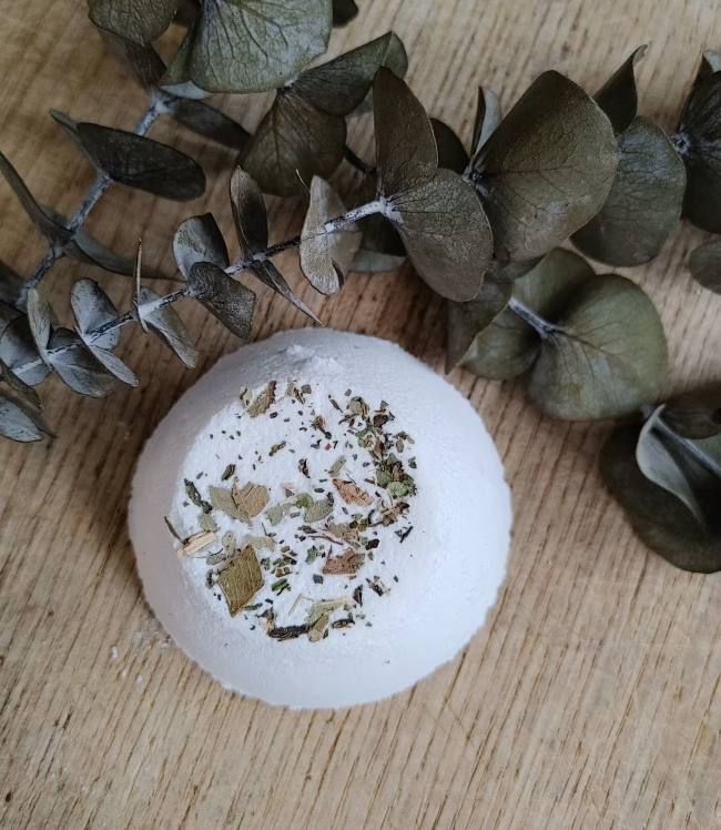 White shower steamer tablet with herb flecks and eucalyptus leaves