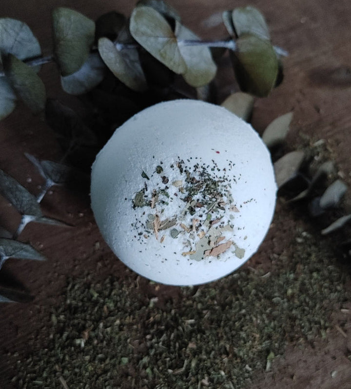 White round bath bomb with dried herb pieces, sprinkled top view