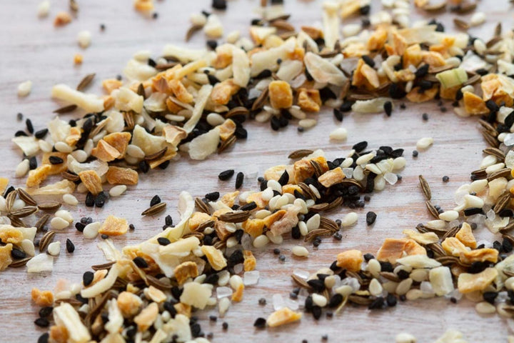 Crushed seeds and spice flakes scattered on a light wooden board