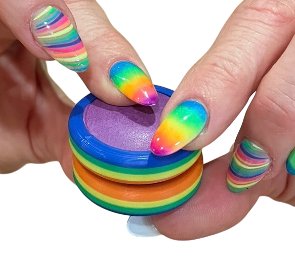 Pride Moons rainbow-striped oval discs held in hands with multicolor nail polish