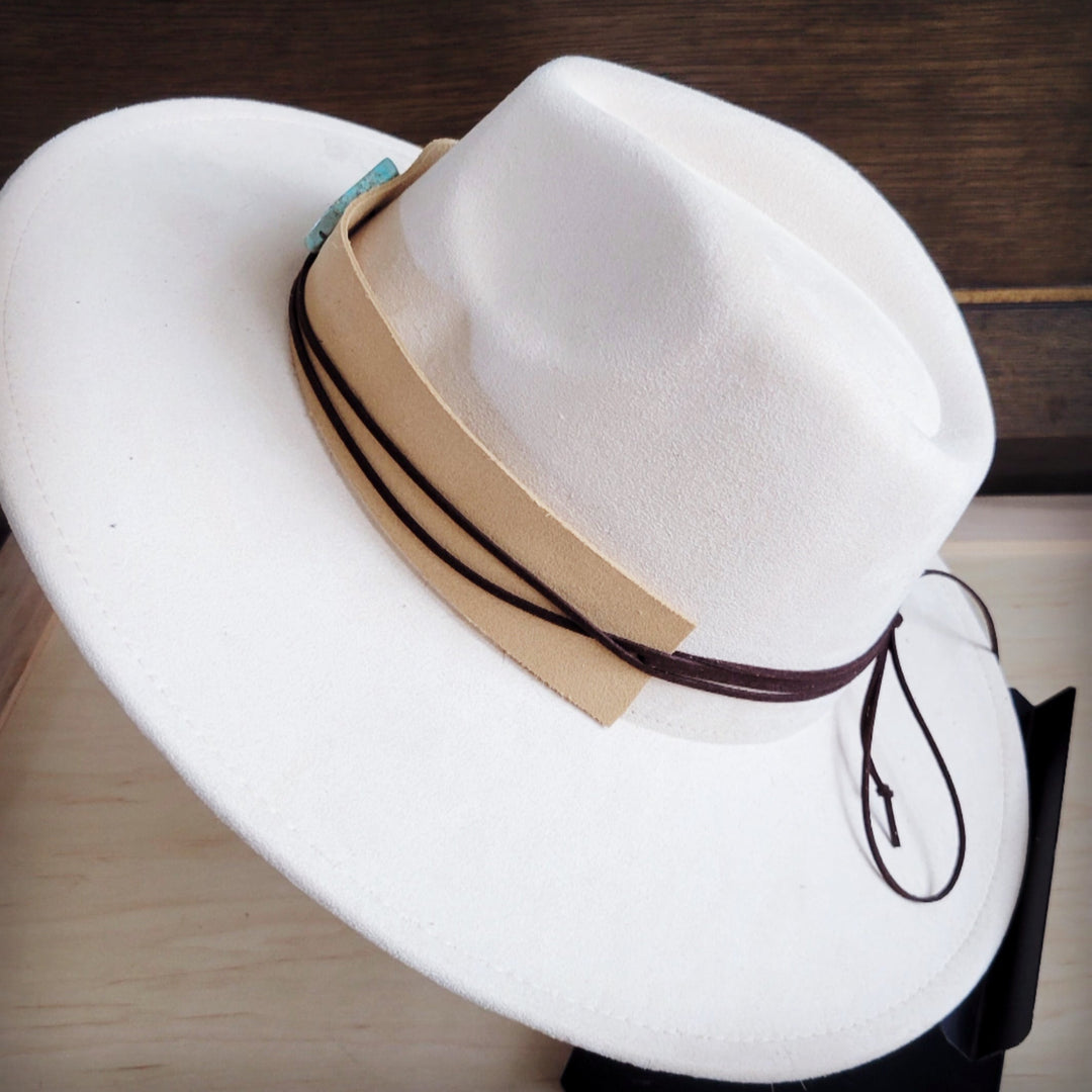 White wide-brim suede hat with tan band and tied dark leather cords