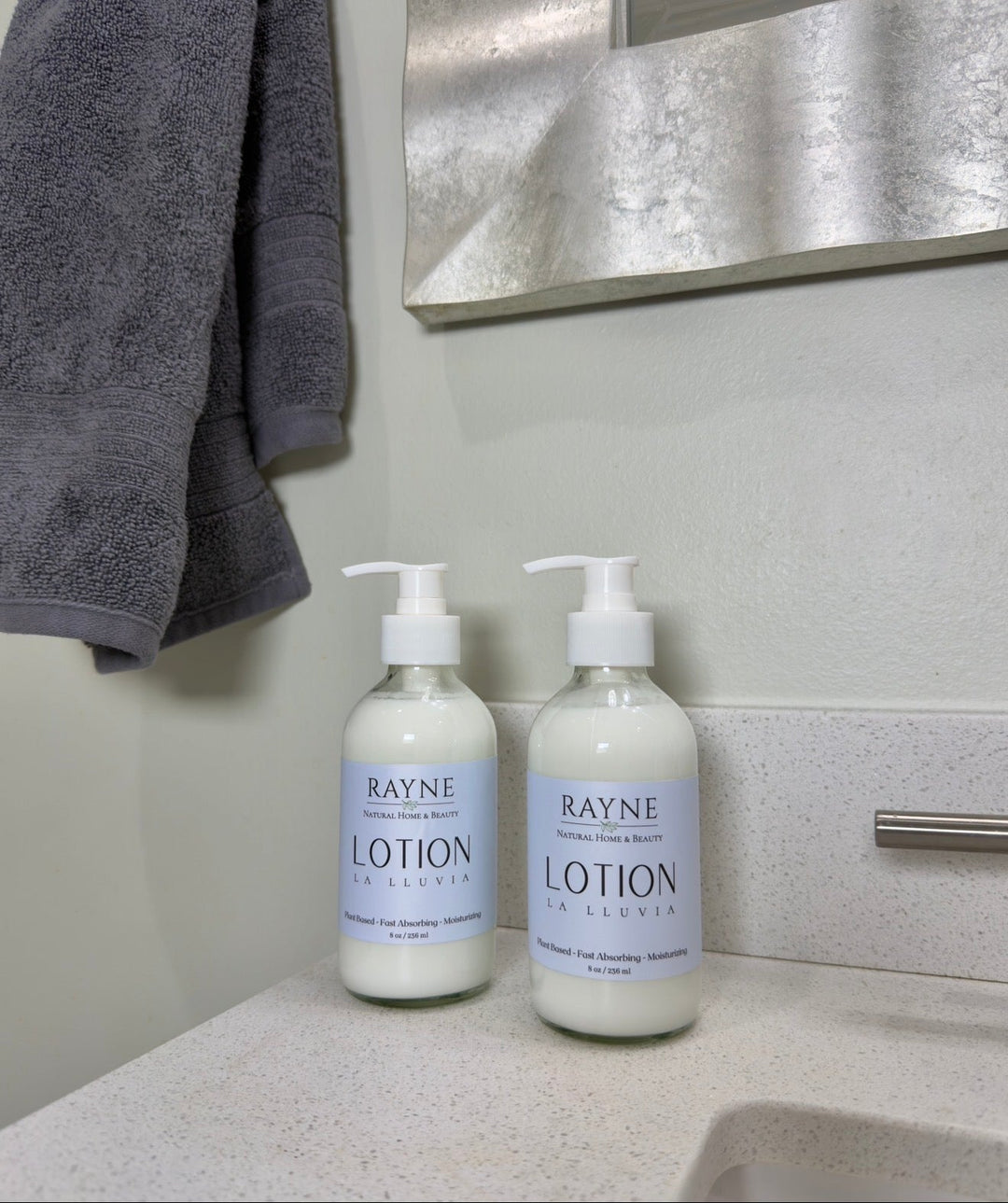 Two moisturizing body lotion pump bottles on countertop near sink, light blue labels.