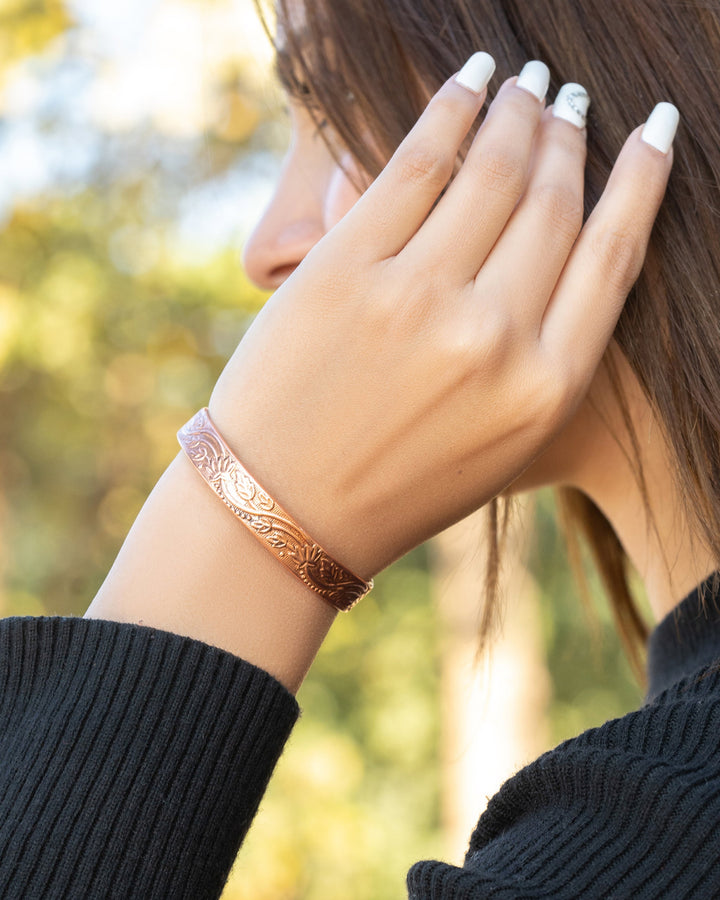 Rose copper floral cuff bracelet on wrist with detailed engraved pattern
