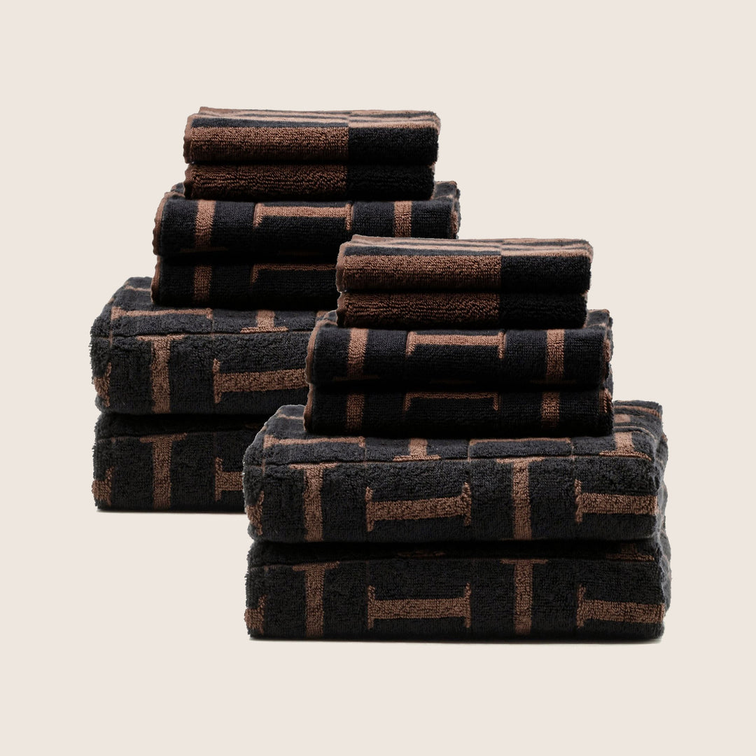 Stack of folded cotton towels in dark base with brown block grid pattern
