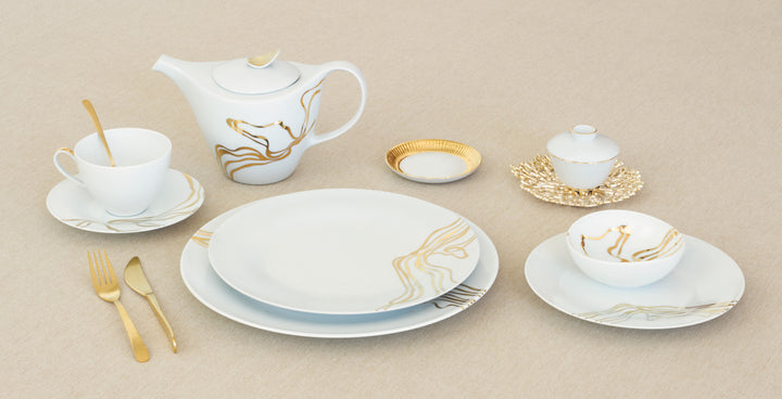 White ceramic cereal bowl with gold swirl design, shown with matching dishes