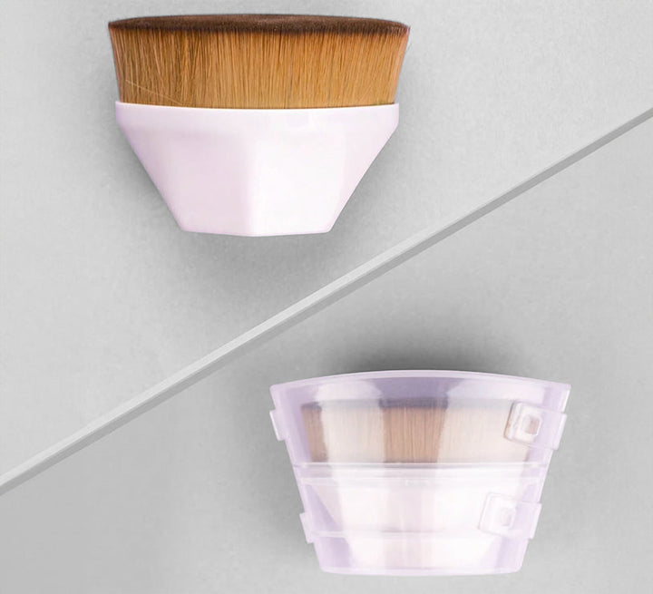 Foundation makeup brush with brown bristles and pastel pink handle beside a storage cup