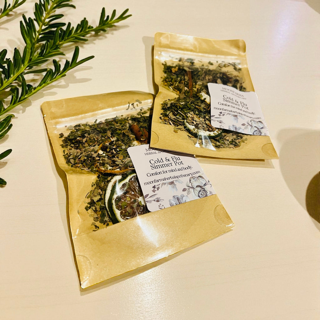 Two kraft paper simmer pot pouches with white labels, dried herbs and rosemary sprig.