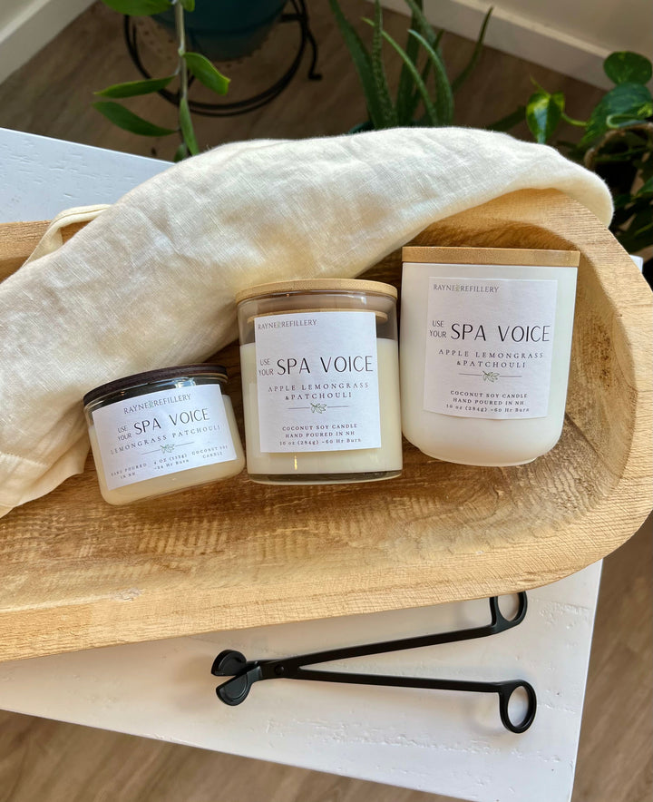 Three white soy candle jars with Spa Voice labels on a wooden tray