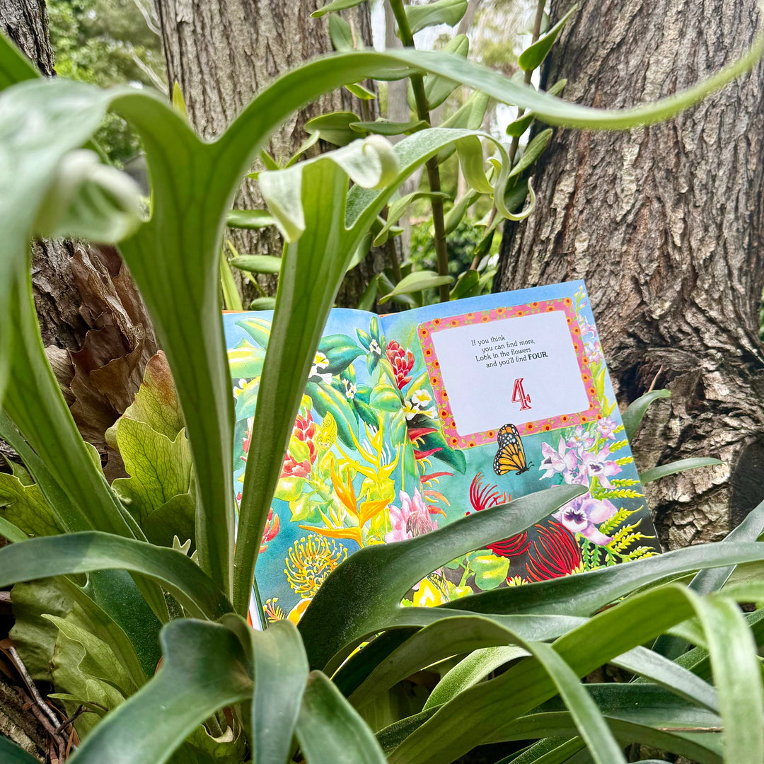 Hardcover illustrated book among green plants with a partial scene on the cover