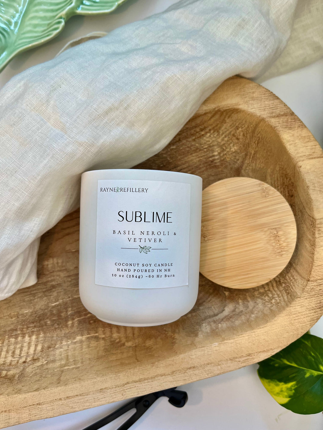 Coconut soy candle in white glass jar with wood lid on wooden tray