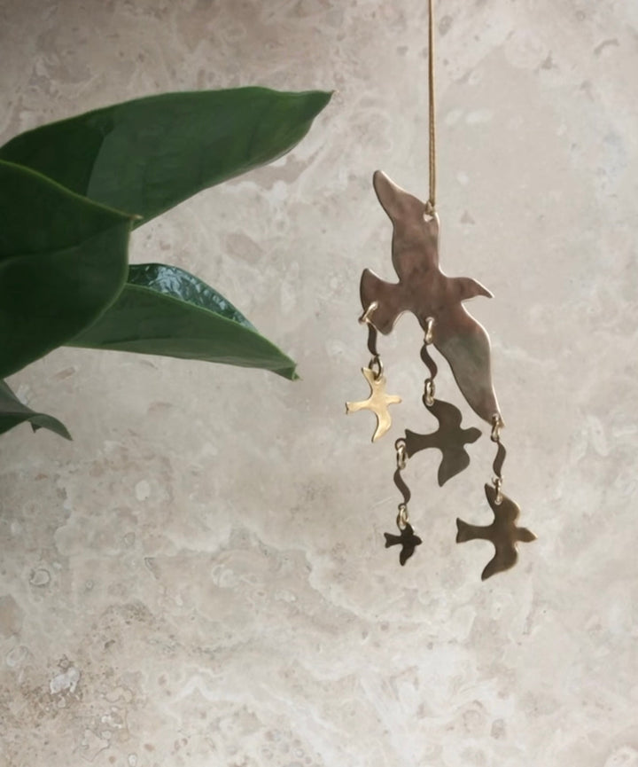 Hanging brass bird ornament with multiple dangling bird charms from a gold string