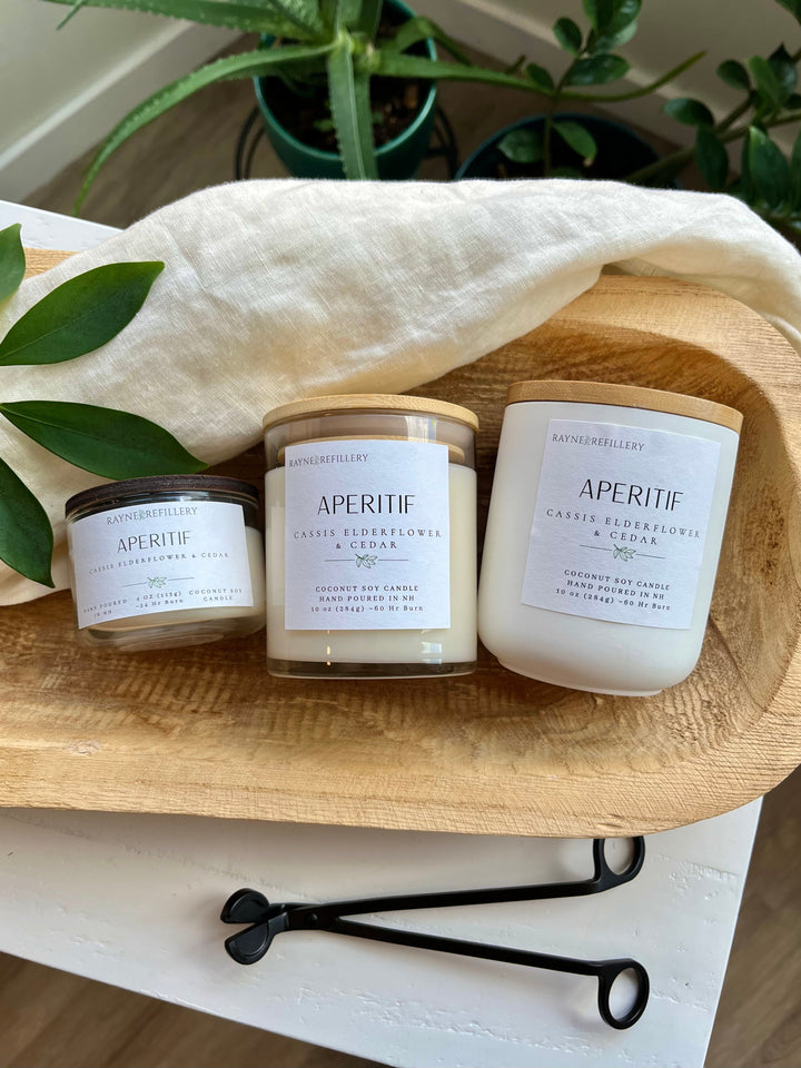 Three white coconut soy candle jars with wooden lids on a wooden tray