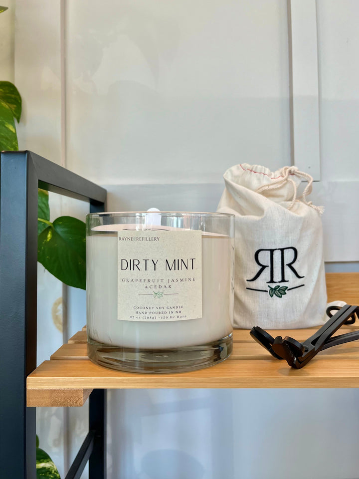 Coconut soy wax candle in clear glass jar with wooden lid on a shelf