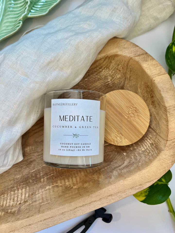Coconut soy candle in clear glass jar with cream label, wood lid beside it