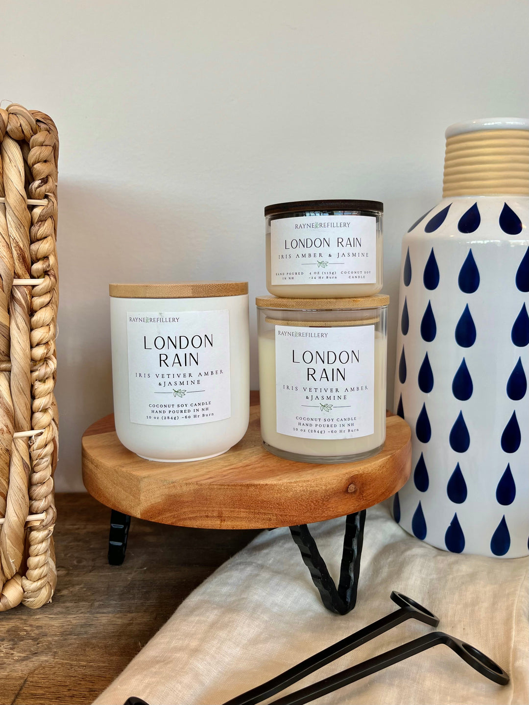 Coconut soy candle in white jar with black lid and printed label on wood tray