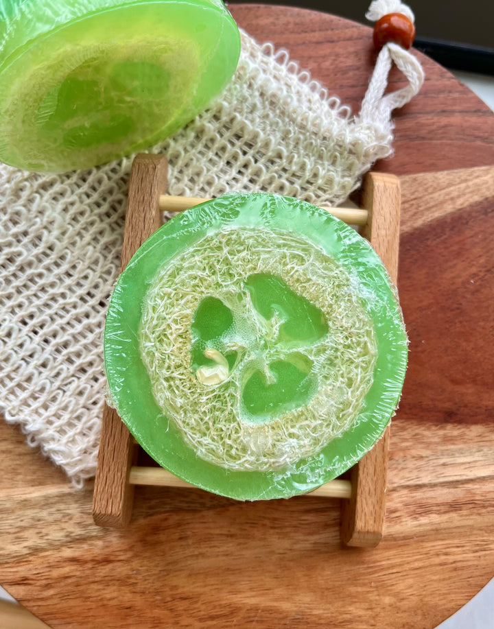 Green loofah soap bar with sculpted circular loofah texture, on a small wooden stand