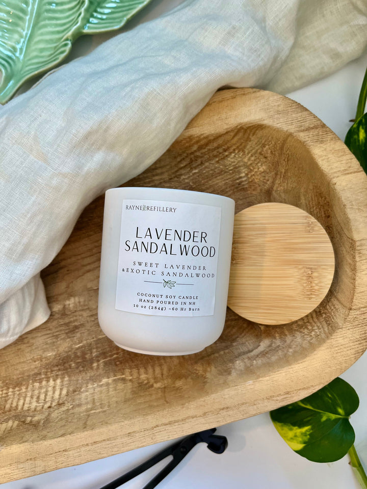 Lavender sandalwood candle in white jar with wooden lid beside on circular plate