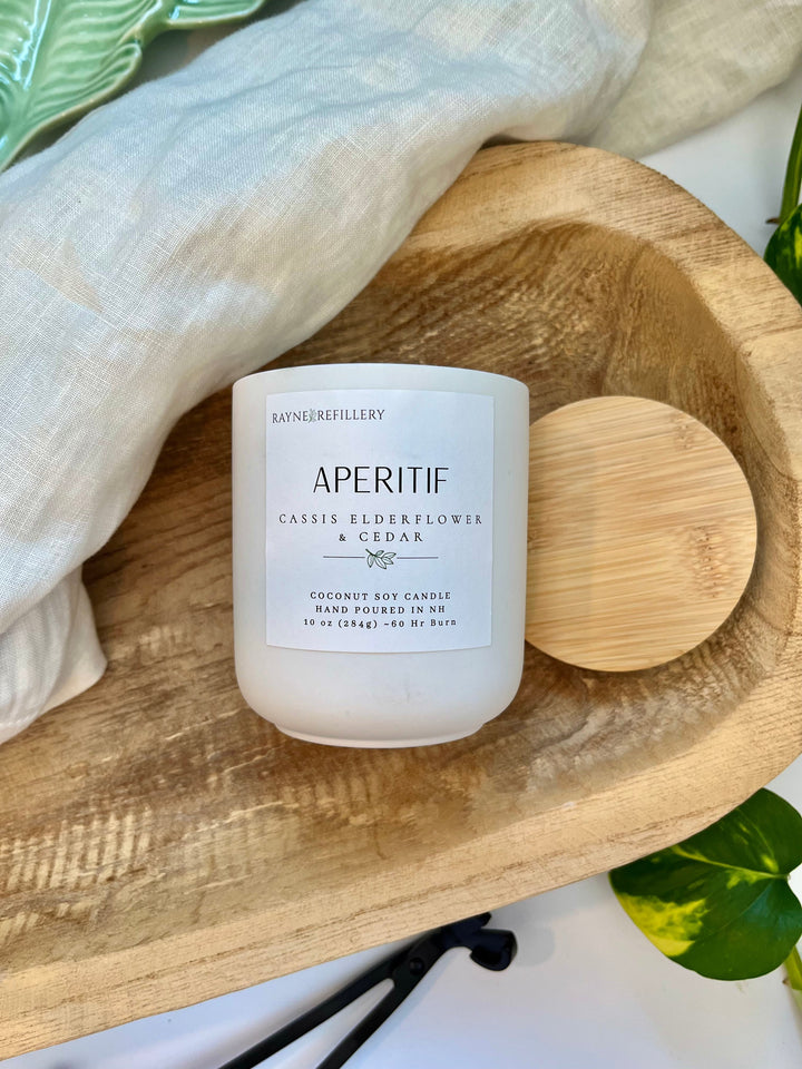 White coconut soy candle jar with wooden lid and label, on round wood tray