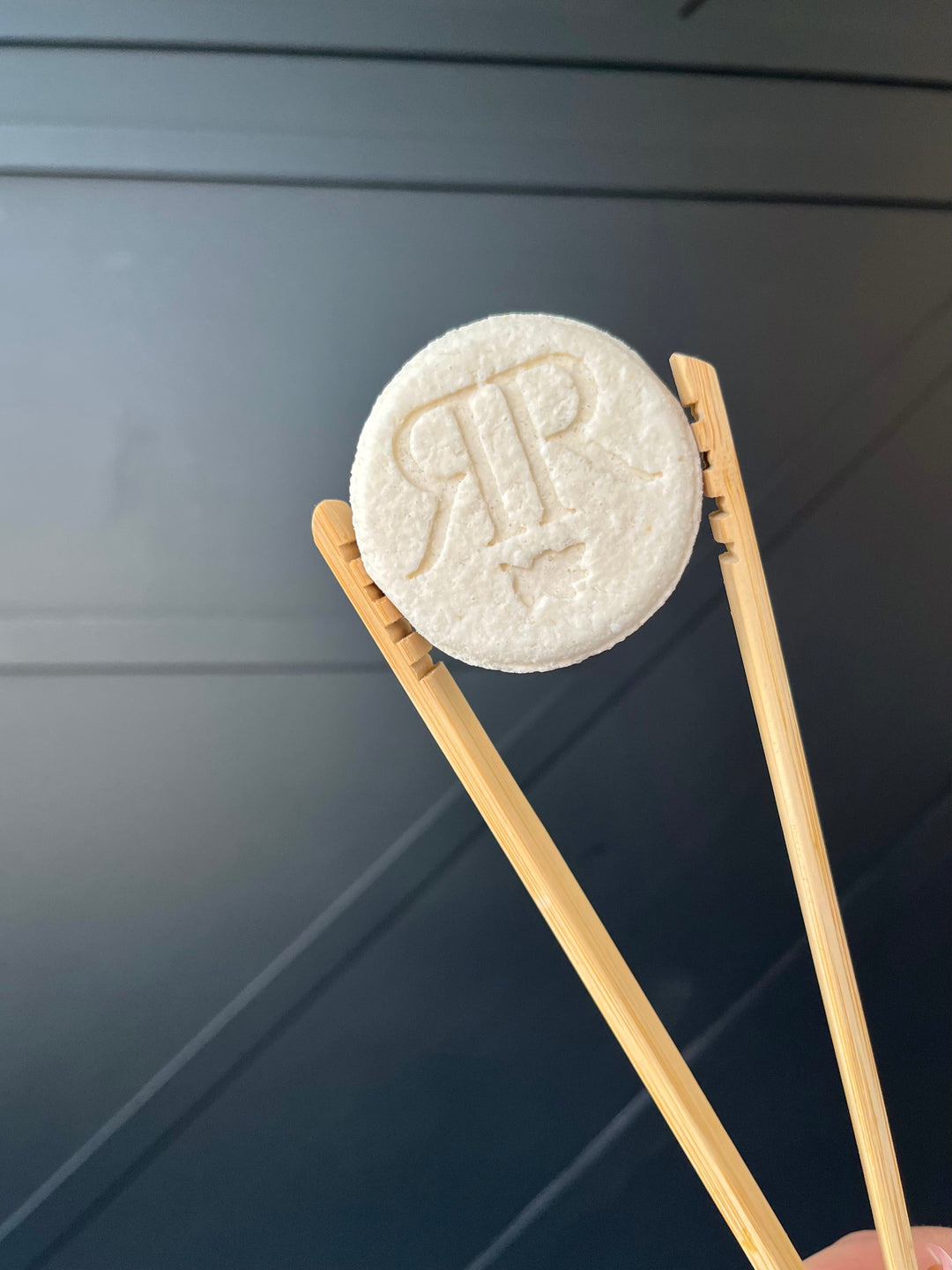Two round shower steamers on bamboo stands, embossed letters on pale tablet tops