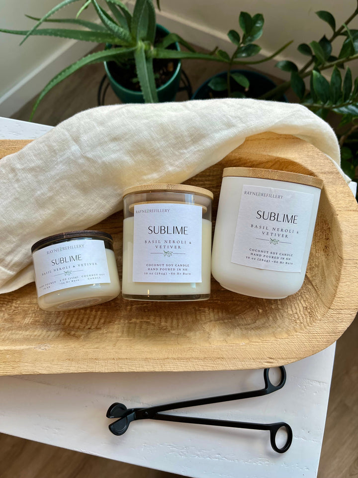 Coconut soy candle trio in white glass jars with wood lids on wooden tray